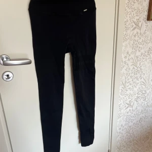 Svarta tights från Stronger - Svarta tights från Stronger med hög midja och ribbad linning. Tight passform och diskret logga framtill. Storlek Xs och normal i storlek. Innerbenslängd: 62 cm. Använda få gånger💕