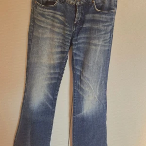 Blå Calvin Klein jeans med brodyr - Snygga blå jeans från Calvin Klein med broderade bakfickor. Klassisk femficksmodell med logotyp på bakfickan och läderpatch i midjan. Jeansen har raka ben och normal passform, perfekta till en avslappnad stil.