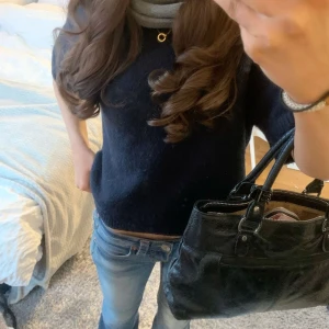 Mörkblå stickad tröja - Mysig mörkblå stickad tröja från Kappahl med rund halsringning och halvlånga ärmar. Perfekt för lager-på-lager och funkar lika bra till jeans som kjol. Tröjan har en enkel och stilren design med ribbade kanter vid ärmslut och nederkant. Str 146-152.