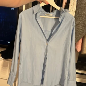 Ljusblå skjorta från Stradivarius XS - Snygg ljusblå skjorta från Stradivarius i storlek XS. Klassisk krage, knäppning framtill och långa ärmar. Perfekt för en clean och stilren look. Skjortan är i ett tunt och skönt bomullsmaterial. V ringning fram. Aldrig använd 