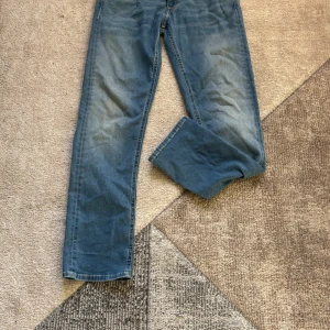 Replay Grover Hyperflex jeans blå - Säljer ett par Replay Grover Hyperflex jeans i klassisk blå tvätt. Modellen har rak passform, fem fickor och snygga detaljer vid bakfickorna. Jeansen är tillverkade i stretchigt denim för extra komfort och rörelsefrihet.