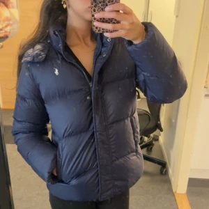 Mörkblå vinterjacka från Ralph Lauren - Aldrig använd, med prislapp kvar på. Super varm och skön. Storlek XL i ungdom vilket motsvarar xs/s. Högsta bud. Köp inte innan att förhandla!! Det är spegel som är smutsig!!!