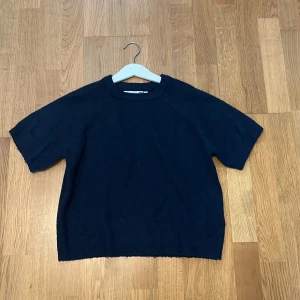 Mörkblå stickad tröja från 157 - En enkel och stilren mörkblå stickad tröja från 157 med korta ärmar, passar till allt. Säljer då den har blivit för liten.