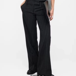 Svarta randiga kostymbyxor low waist - Snygga svarta lågmidjade kostymbyxor med tunna vertikala ränder och låg midja. Byxorna har en rak och lite vidare passform med klassisk look. Med en tillhörande topp. (Lappar kvar, nypris 800kr) storlek 36 på byxorna o s på toppen.