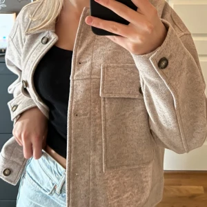Beige kort kappa med stora fickor - Säljer en beige kort kappa med stora bröstfickor och snygga knappar framtill. Jackan har en loose passform och är tillverkad i ett mjukt ull-liknande material. Nypris 1250. Använd ca 2-5 gånger absolut inte fler än 5:(