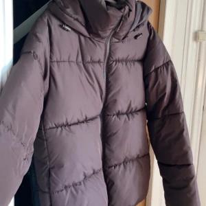 Brun pufferjacka från Cubus XS - Säljer en brun pufferjacka från Cubus i storlek XS. Perfekt för kalla dagar. Enkel och stilren design som håller dig varm hela vintern.