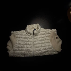 Moncler cardigan storlek S - Moncler cardigan med quiltad framsida och ärmar i mjuk stickad kvalitet. Jackan har dragkedja framtill och en liten logga på ärmen. Perfekt för dig som vill ha en clean och stilren look. Har äkthetsbevis i form av prislapp och kvitto. Nypris 8400kr