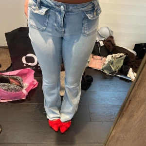 Ljusblå bootcut jeans med fickdetaljer - Säljer ett par ljusblå jeans med bootcut-modell och snygga fickdetaljer framtill. Jeansen har medel midja och är tillverkade i klassiskt denimtyg. Perfekta för dig som gillar en retroinspirerad look med lite extra edge. PRIS GÅR ATT DISKUTERA 