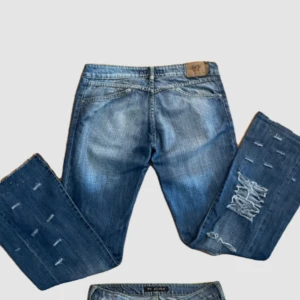 Blå bootcut jeans med slitningar - Snygga blå jeans med bootcut passform och slitna detaljer på benen.  Perfekta för dig som gillar en avslappnad och trendig look. 