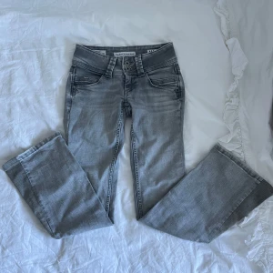 Grå bootcut jeans från Pepe Jeans - Snygga grå jeans från Pepe Jeans med bootcut passform och låg midja. Jeansen har coola detaljer som dubbla knappar i midjan, klassiska bakfickor med broderi. Perfekta för en avslappnad och trendig look. Super bra skick. De är omsydda till bootcut men det är jätte fint sytt. Fråga om bilder med mått. W24 L30