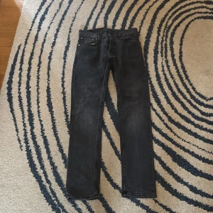 Grim Tim dark cove Nudie Jeans Co W30 L32 - Säljer ett par svarta jeans från Nudie Jeans Co i storlek W30 L32. Jeansen har klassisk femficksdesign, raka ben och subtilt slitna detaljer. Perfekta för dig som gillar en enkel och stilren look. Materialet är jeans och färgen är mörksvart. Använda sparsamt och säljs pågrund av att dom är för små