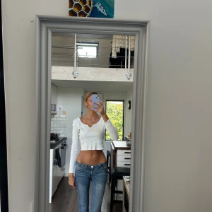 Vit croppad ribbad långärmad topp - Säljer en vit croppad topp från Gina tricot med lång ärm och ribbad struktur. Toppen har en snygg v-ringning med liten slits framtill och är figurnära i passformen. Perfekt att matcha med jeans eller kjol för en chill look.