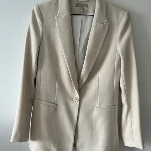 Kavaj - Ljus beige kavaj ifrån HM i storlek 38 med fickor och enkel knapp på mitten fram.