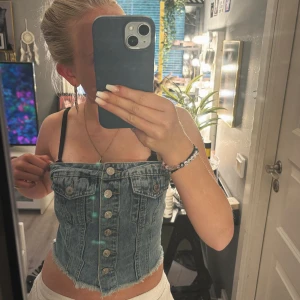 Blå jeanskorsett med knappar - Säljer en croppad jeanskorsett i ljusblå denim med snygga silverfärgade knappar framtill💘🫰