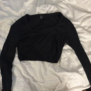 Svart croppad långärmad topp Shein - Svart croppad topp från Shein med lång ärm och rund halsringning. Toppen är ribbad och har en tight passform som sitter snyggt på kroppen. Perfekt att styla med höga jeans eller kjol för en trendig look.