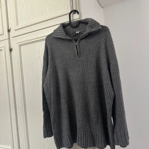 Grå ribbad stickad tröja med half zip - Mysig grå stickad tröja från Gina Tricot med ribbad struktur och half zip i halsen. Perfekt för lager på lager och har en avslappnad passform med långa ärmar och hög krage. Enkel att styla till jeans eller leggings.