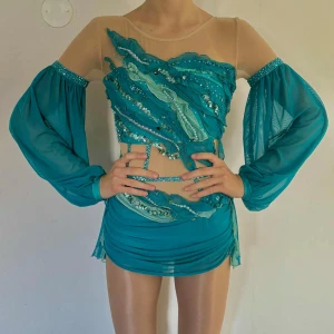 Turkos/blå tävlingsdräkt dans! - Superfin uppsydd turkos tävlingsdräkt tidigare använd till modernt solo. Inköpspris 3000kr! Som alldeles ny i storlek som motsvarar xs/s. Riktiga swarovskistenar, airbushmetoder, pärlor, paljetter och massa detaljer!