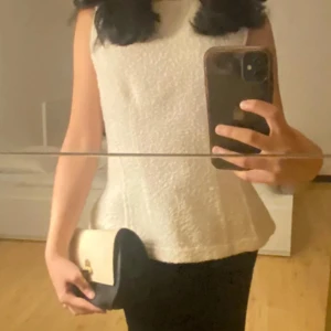 Svart och beige handväska - Snygg handväska från Fiorelli i svart och beige skinn med guldfärgat spänne framtill. Väskan har en stilren, rundad form och är perfekt för att bära det viktigaste. Klassisk design som passar till många outfits.