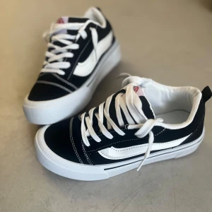 Svarta och vita sneakers med vit sula - Klassiska Vans Old Skool-inspirerade sneakers i svart och vitt med vit sula och vit sidestripe. Skorna har snörning, vit tå och kontrasterande sömmar. Ovandelen är i canvas och mocka, insida i textil och yttersulan är gummimönstrad för bra grepp.