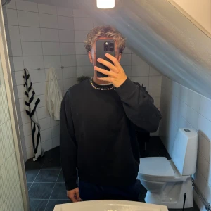 Svart sweatshirt från Acne Studios - Säljer en svart sweatshirt från Acne Studios med logga runt kragen. Tröjan har en klassisk passform, rund halsringning och långa ärmar. Perfekt för dig som gillar stilrena och trendiga plagg med diskret branding.