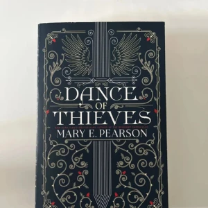 Dance of Thieves - En snyggt designad bok med mörk omslag och eleganta, silvriga detaljer. Perfekt för dig som gillar spännande berättelser och vill ha något stilrent i bokhyllan. Passar unga vuxna som söker äventyr och mystik.