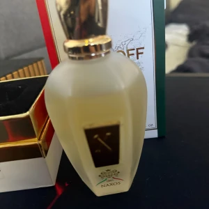 Xerjoff Naxos Eau de Parfum 100ml - Lyxig parfym från Xerjoff, Naxos, i en frostad glasflaska med gulddetaljer och elegant lock. Flaskan har en unik form och kommer med originalförpackning i vitt, rött och grönt med guldfärgad kant. Volymen är 100 ml.