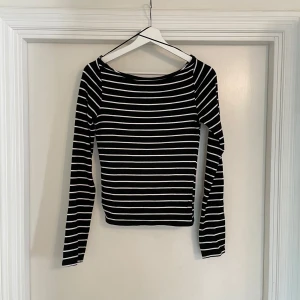 Svartvit randig långärmad från gina topp - Svart långärmad topp med vita horisontella ränder och slits vid ärmsluten. Snygg, enkel och passar perfekt till jeans eller kjol. Mjuk och stretchig bomullskänsla med en klassisk rund halsringning.