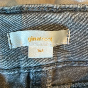 Grå jeans med bootcut från Gina Tricot - Snygga grå jeans från Gina Tricot i storlek 146. Modellen har bootcut-ben, klassiska fem fickor och dubbla knappar framtill. Jeansen är i mjukt denimtyg och har en stilren, enkel look som passar till det mesta.