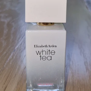 Elizabeth Arden White Tea Wild Rose - Fräsch parfym från Elizabeth Arden, White Tea Wild Rose. Flaskan är rektangulär med en vit och transparent design, och har en stor vit fyrkantig kork med gulddetalj. Perfekt för dig som gillar blommiga och eleganta dofter.