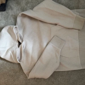 Beige ribbad hoodie från zara - Säljer en beige hoodie från H&M med ribbad struktur och stor huva. Tröjan har långa ärmar med breda muddar och en stor magficka framtill. Perfekt för chill dagar och enkel att matcha med jeans eller mjukisbyxor.