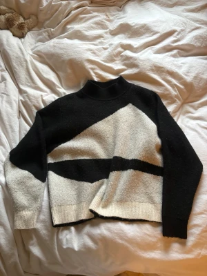Stickad tröja ifrån Vila - Super gosig och fin tröja ifrån Vila. Svart och vit på framsidan och ena ärmen och helt svart på baksidan. Använd fåtal gånger men fortfarande väldigt bra skick. Går upp lite vid halsen och super skön nu till vintern !🥰