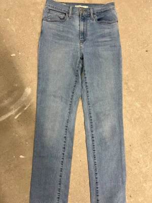 Levi's 724 High Rise Straight jeans - Snygga ljusblå Levi's Premium 724 High Rise Straight jeans i klassisk femficksmodell. Hög midja och raka ben ger en chill och tidlös vibe. Jeansen har Levi's ikoniska läderpatch och röda tab på bakfickan. Perfekt för dig som gillar enkel och clean denimstil.