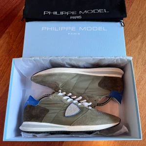 Philippe Model sneakers i olivgrönt - Snygga Philippe Model sneakers i olivgrönt med detaljer i mocka och mesh. Skobox och skopåse ingår i köpet. Nypris 309 CHF vilket motsvarar ungefär 3650 kr. Var inte rädda att skriva vid minsta lilla fundering, Pris kan diskuteras vid snabb affär.