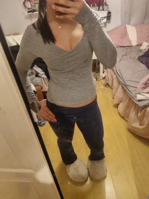 Grå v-ringad långärmad tröja - Säljer en grå långärmad tröja med v-ringad hals och tight passform. Tröjan har en snygg omlott-look vid halsen och är perfekt för dig som gillar stilrena och enkla plagg. Passar dig som vill ha en basic men ändå trendig topp.