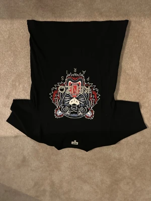 Kenzo T-shirt - Asfet svart tisha från märket kenzo, andvönd sparsamt och i nästintill nytt skick, najsigt tryck frampå, märkets logotyp som är asfet! Skriv om du undrar nåt🍾