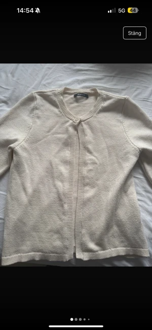 Beige kofta från Gina Tricot - Snygg beige kofta från Gina Tricot med rund halsringning och ribbade kanter. Koftan har en enkel knapp framtill och är långärmad. Perfekt att slänga över en t-shirt eller linne för en chill look. Tröjan är i fint skick men kan upplevas nopprig. 