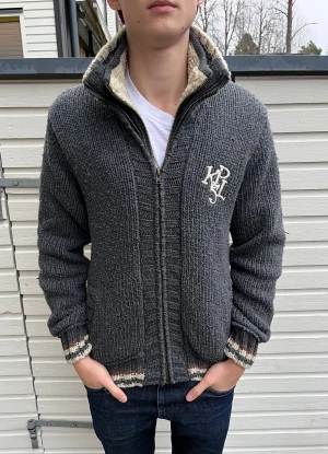 Stickad kofta med foder  - Mysig grå stickad cardigan jacka från Kaporal med broderad logga på bröstet. Skick 8.5/10 riktigt bra med små tecken på användning! Nypris ligger runt 2500kr men säljs nu för 899kr. Hör gärna av er vid minsta lilla fundering.