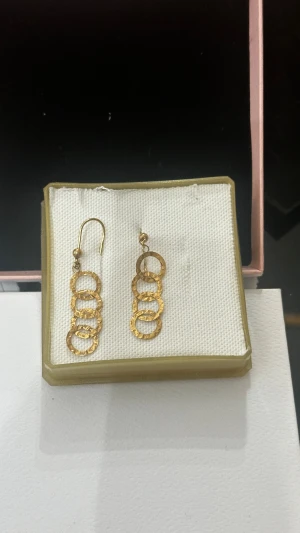 Guldiga örhängen med ringar från mango - Unika örhängen i guldton med fyra sammankopplade, hamrade ringar som ger en cool och modern vibe. Hängande modell med enkel krok och snygg struktur på metallen. Perfekt för dig som gillar statement-smycken med lite edge.