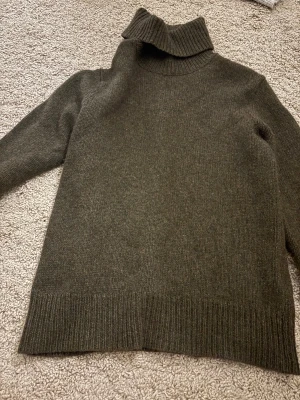 Mörkgrön polotröja från Ralph Lauren - Säljer en mörkgrön polotröja från Ralph Lauren i lyxig mix av kashmir och ull. Tröjan har lång ärm, ribbade muddar och en hög, mjuk polokrage. Perfekt för dig som gillar klassisk stil med premiumkänsla.