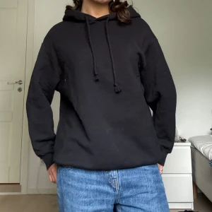 Svart hoodie med huva och snörning - En klassisk svart hoodie med huva och snörning. Extra najs utan ficka framtill!