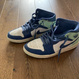 Nike Air Jordan 1 Mid blå/vit/grön - Säljer mina Nike Air Jordan 1 Mid sneakers i blått, vitt och ljusgrönt. Klassisk siluett med snörning, perforerad tå och air Jordan-logga på sidan. Ovandel i skinn och syntet. Rätt så bra scick 