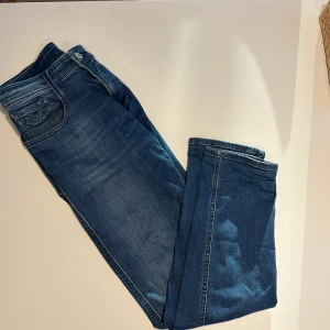 Blå Replay ambass jeans  - Säljer ett par klassiska blå jeans från Replay med snygg tvätt och raka ben. Jeansen har fem fickor, tydliga sömmar och Replay-logga på bakfickan samt läderpatch i midjan. Perfekta för dig som gillar en tidlös jeanslook. Modellen heter ambass