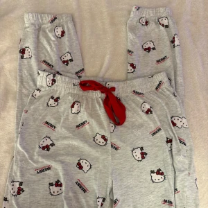 Hello Kitty pyjamasbyxor Sanrio grå - Grå mjuka pyjamasbyxor från Sanrio med Hello Kitty-motiv och texten 'Merry Christmas' över hela byxan. Perfekta för mysiga hemmakvällar och har ett gulligt juligt print. Använt 1 gång