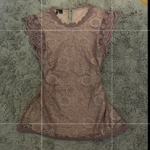 Gammeldagsrosa spetsblus - Supersöt gammeldags rosa blus med vackra spetsdetaljer och volang vid ärmarna. Blusen har ett unikt mönster och rund halsringning. Perfekt för dig som vill sticka ut på ett elegant sätt. Passar storlek xs-m.