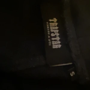 Svart Trapstar byxor med tryck - Svarta byxor från Trapstar i storlek S med färgstarkt tryck på bröstet där loggan är i rött, grått och vitt. 