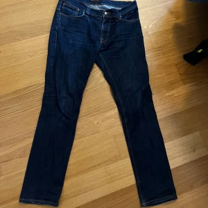 Mörkblå jeans från Nudie Jeans Co - Snygga mörkblå jeans från Nudie Jeans Co med klassisk femficksdesign och kontrastsömmar. Jeansen har raka ben och coola broderade bakfickor. W33 L32 men sitter mer som W31