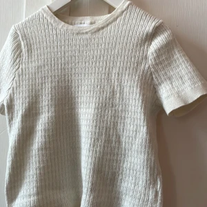 Vit ribbad t-shirt från Zara - Superfin vit t-shirt från Zara med ribbad struktur och diskret mönster. T-shirten har korta ärmar och rund halsringning. Perfekt för en clean och stilren look, lätt att matcha med allt. Materialet känns mjukt och bekvämt.