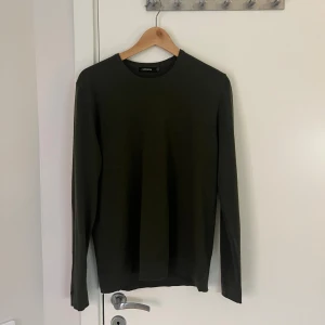 Olivgrön stickad tröja J.Lindeberg - Säljer en olivgrön stickad tröja från J.Lindeberg i storlek M. Tröjan har rund halsringning, diskret broderad logga på bröstet och är långärmad. Tröjan är i bra skick, tveka inte på att höra av dig vid frågor eller funderingar! Priset kan diskuteras.