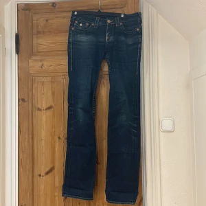 True Religion blå skinny jeans - Snygga blå skinny lowwaist jeans från True Religion med klassiska kontrastsömmar och stora fickor bak med knappar. Köpte dem här på plick och själv har jag använt dem ett fåtal gånger. De är i utmärkt skick förutom där fram på färgen☺️