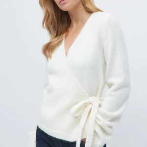 Vit omlottkofta från Gina Tricot - Supermysig vit omlottkofta från Gina Tricot med v-ringning och knyt i sidan. Koftan har långärmade ärmar och är stickad i ett mjukt material som känns lyxigt. Perfekt att styla med jeans eller kjol för en chill look. Endast använd 2-3 ggr. Säljer denna för 300kr